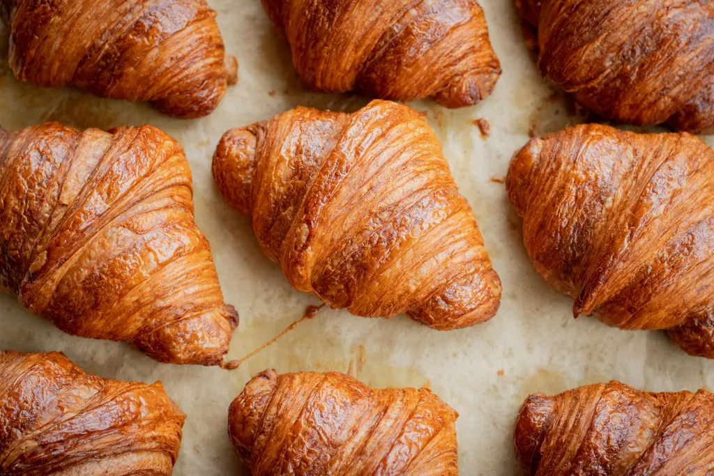 Bandeja de croissants dorados sobre papel de horno